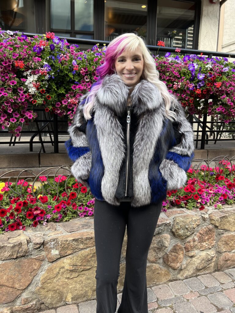 Person in a blue and gray fox fur jacket with a fluffy texture and bold design by Fantasia Furs.