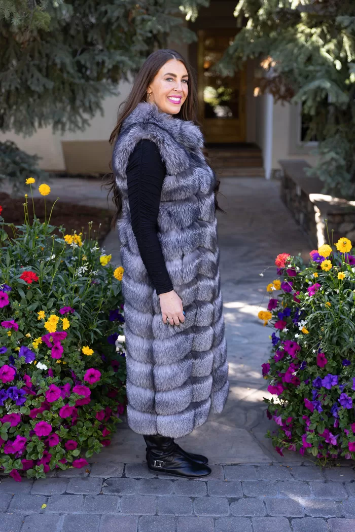 Natural Silver Fox Duster Vest brings luxurious style and warmth to any outfit. The soft silver fox fur showcases its natural blend of gray, black, and white tones, creating a stunning visual effect. The long duster design adds elegance, making it a perfect statement piece for any occasion.