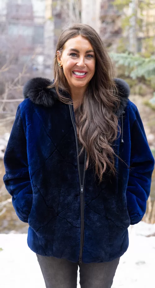 Our dyed royal blue ombre sheared beaver zip-up jacket with hood and dyed black fox trim showcases stunning color and bold contrast. The hood adds extra warmth and style. Additionally, the black fox trim highlights the jacket’s unique design. You will enjoy modern elegance and standout flair.